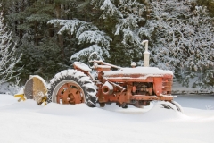 Snow covered rustic farm tractor